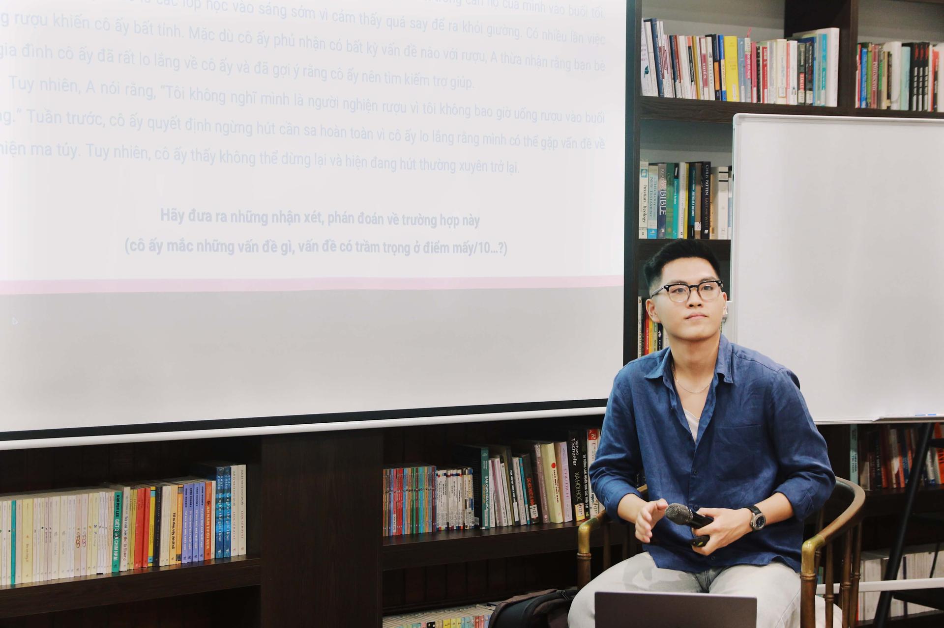 Người trình bày ngồi trước màn chiếu, trình bày một trường hợp nghiên cứu.
